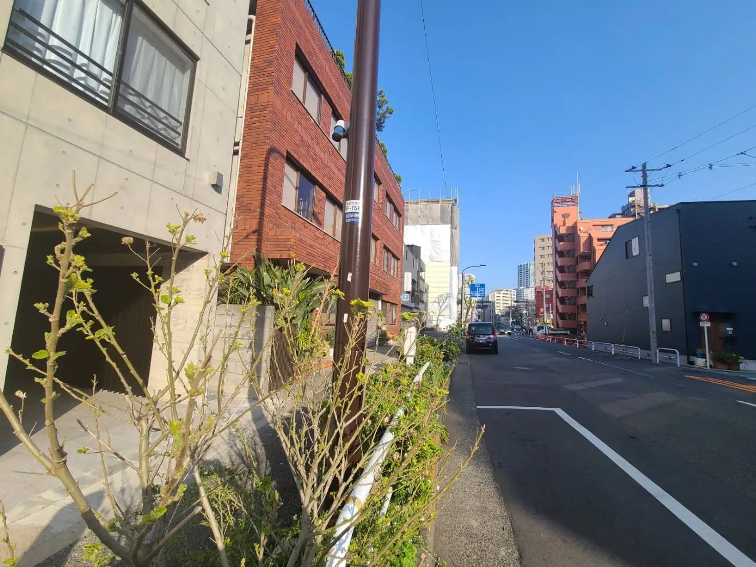 都市の静かな住宅街、日当りの良い通り、赤レンガとグレーのモダンな建物