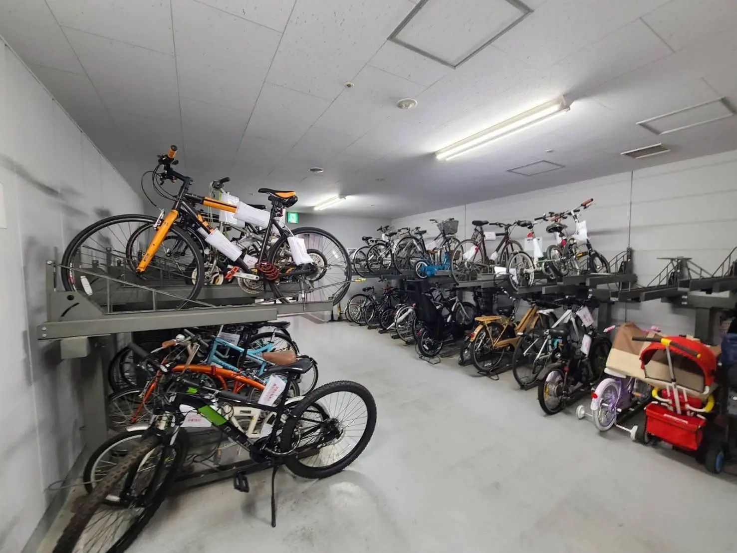 整理された自転車駐輪場、二段式ラックに収納された多様な自転車とキッズカート