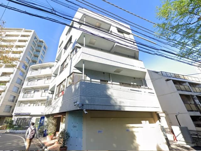 都市の日当たりの良い角地にあるモダンなマンション、歩行者と街路樹が見える外観