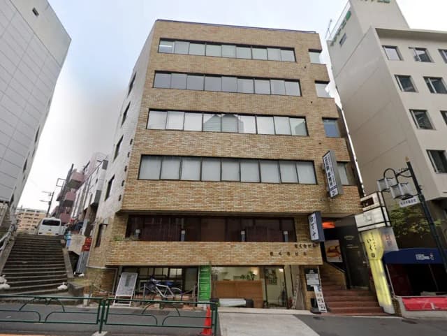 都市環境に位置するモダンなビルの外観、煉瓦造りのファサードと窓、通り沿いにお店の看板