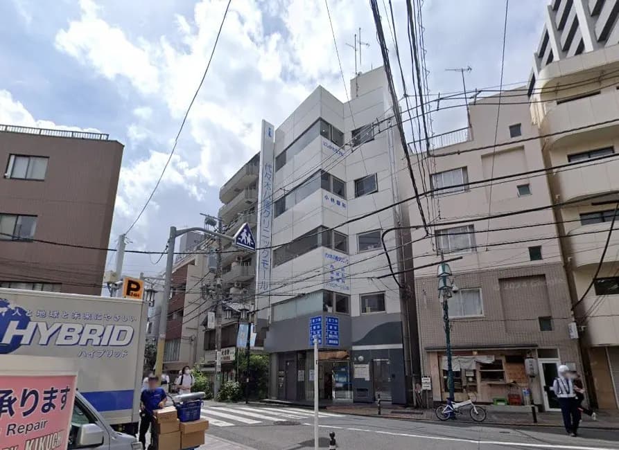 電線が交差する市街地の風景、道路標識と複数の建物、曇り空