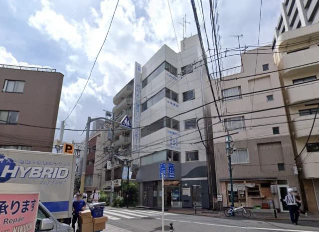 電線が交差する市街地の風景、道路標識と複数の建物、曇り空