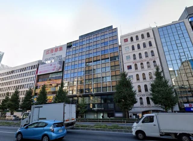 東京都内のビル並みと通り、朝の通勤時間帯、様々な建築スタイルと広告看板を備える都市風景