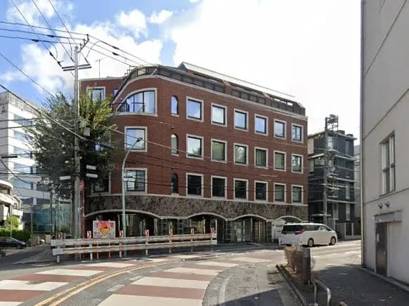 都市の交差点にあるモダンな赤レンガ造りのオフィスビル、晴天の下でのクリアな外観