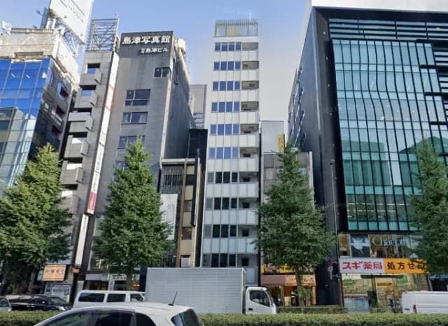 日本の都会の通りに面した現代的なオフィスビルと商業ビル、緑豊かな植栽と晴れた青空