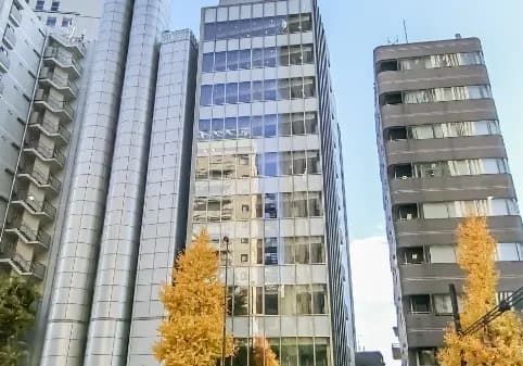 秋の季節に黄金色に輝くイチョウの木と、都市のオフィスビルが並ぶ風景