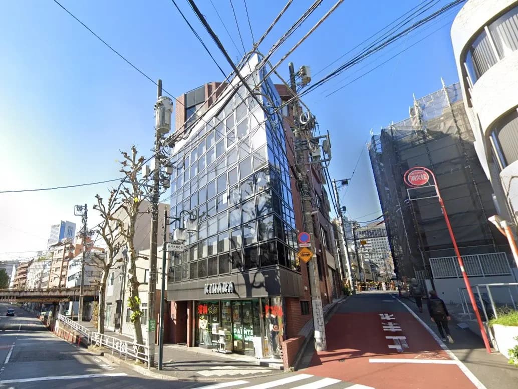 都市の一角に位置する日本の通り、晴れた日の青空と建物、電線が交差する風景