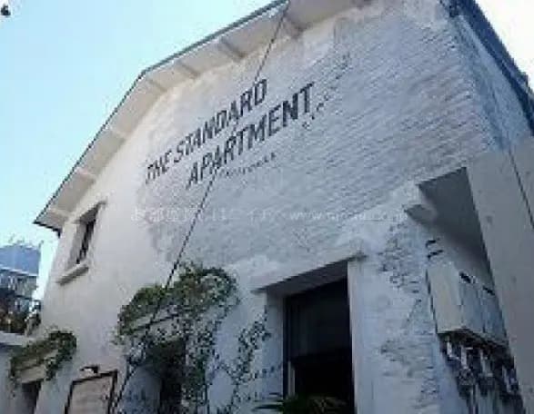 外壁に大きな文字で「THE STANDARD APARTMENT」と印字された現代的なアパートメントの外観