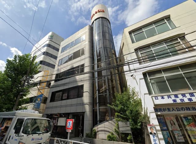 日本の都市部にある現代的な建築のオフィスビル、ガラス張りの円筒形部分と電線が交差する屋外シーン