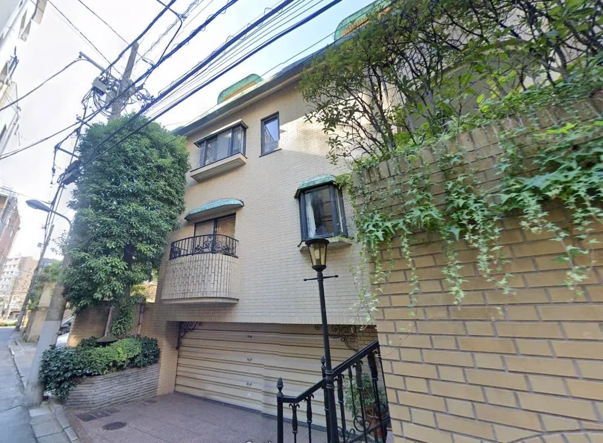 都市の一角にあるモダンな外観の住宅、ガレージ付き、緑豊かなツタが壁を覆う