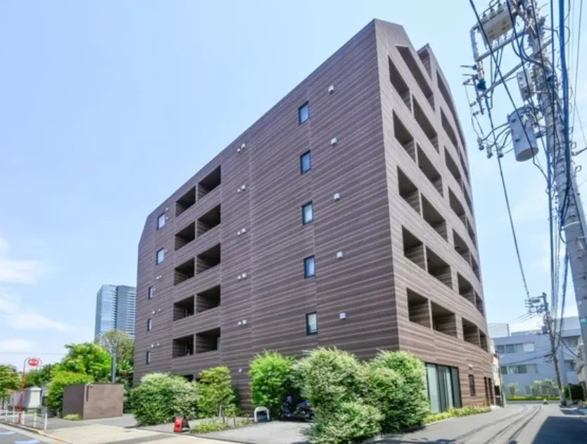 - モダンなデザインのアパートメントビル、木目調の外観と大きな窓が特徴、周囲には緑豊かな植栽がある街並み