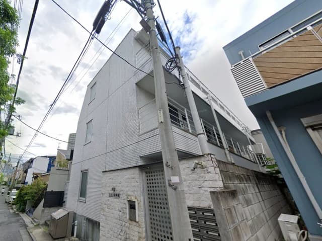 日本の住宅街にあるモダンな外観のアパート建物、電柱と電線が交差する街角