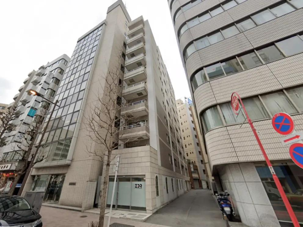 - 都市のビル群に囲まれた現代的な外観の建物、ガラスのファサードとバルコニーが特徴の商業用ビル