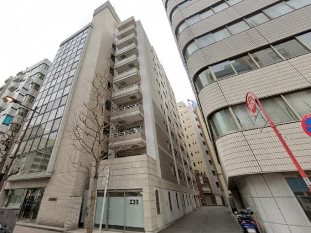 - 都会的な雰囲気の中に立つモダンなビル群、白い外壁とガラス面が特徴的な建物が並ぶ街並み