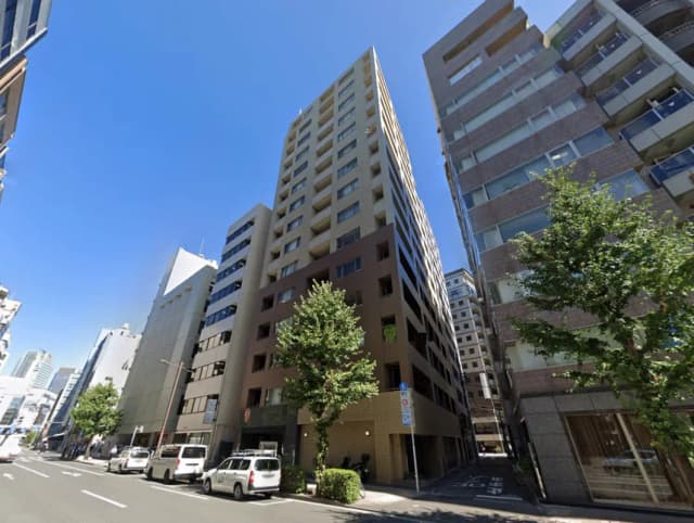- 都市部に位置する高層ビル群、青空の下で見える現代的な建築様式と木々の緑が調和した街並み