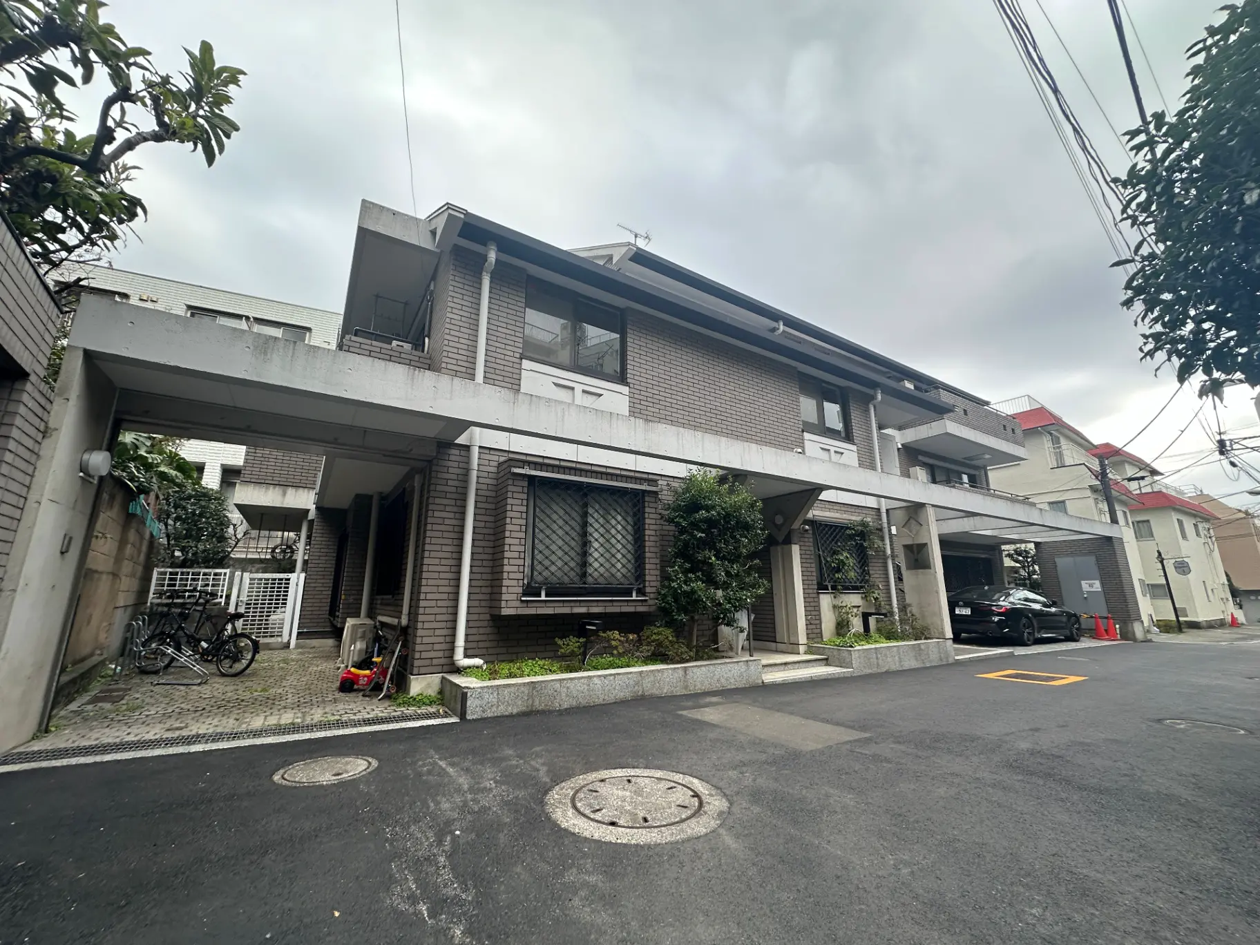都市部の住宅街にある現代的なデザインの住宅、車と自転車が停まっている外観