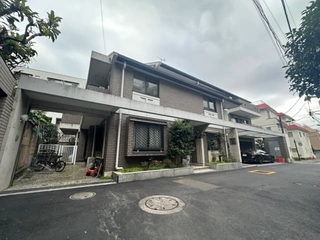 都市部の住宅街にある現代的なデザインの住宅、車と自転車が停まっている外観