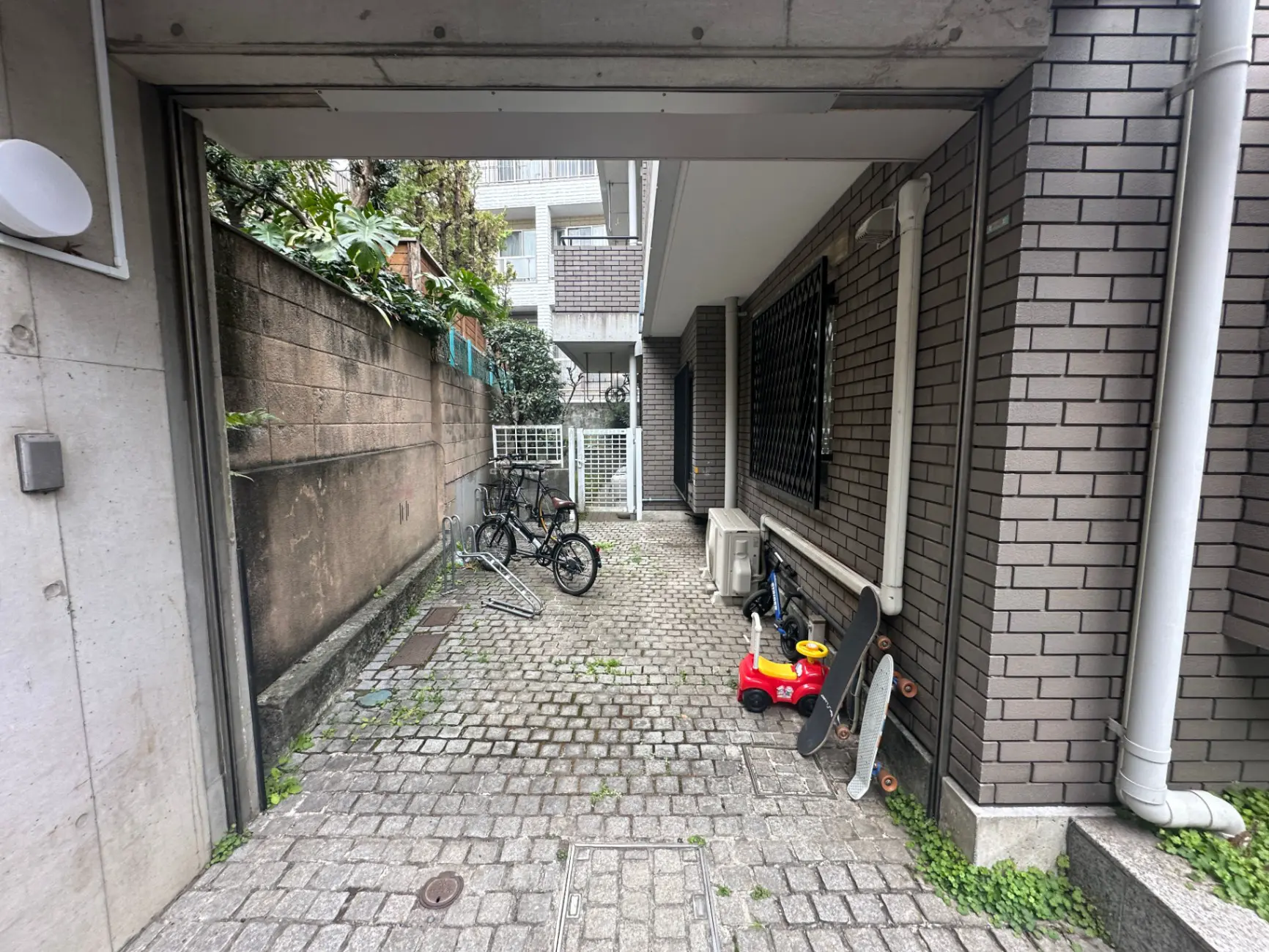 都市の狭い路地にある自転車と子供の乗り物玩具が置かれた住宅街の風景
