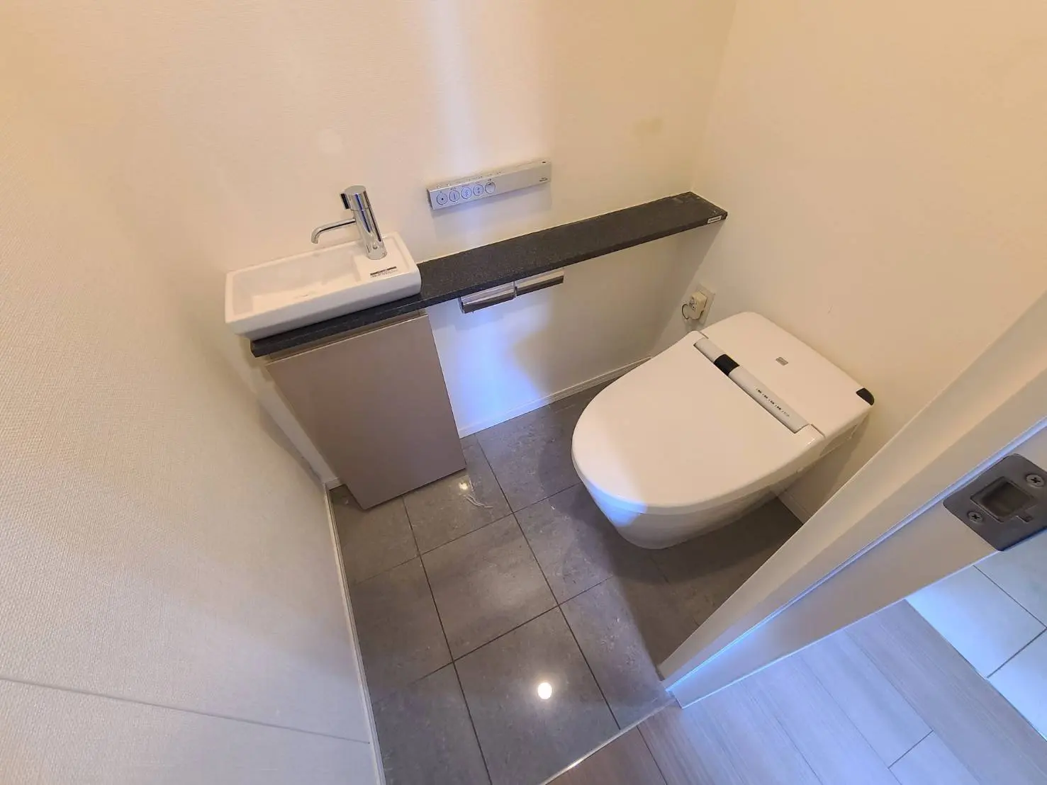 コンパクトな洗面台と最新式トイレが備わった清潔感のあるトイレルーム