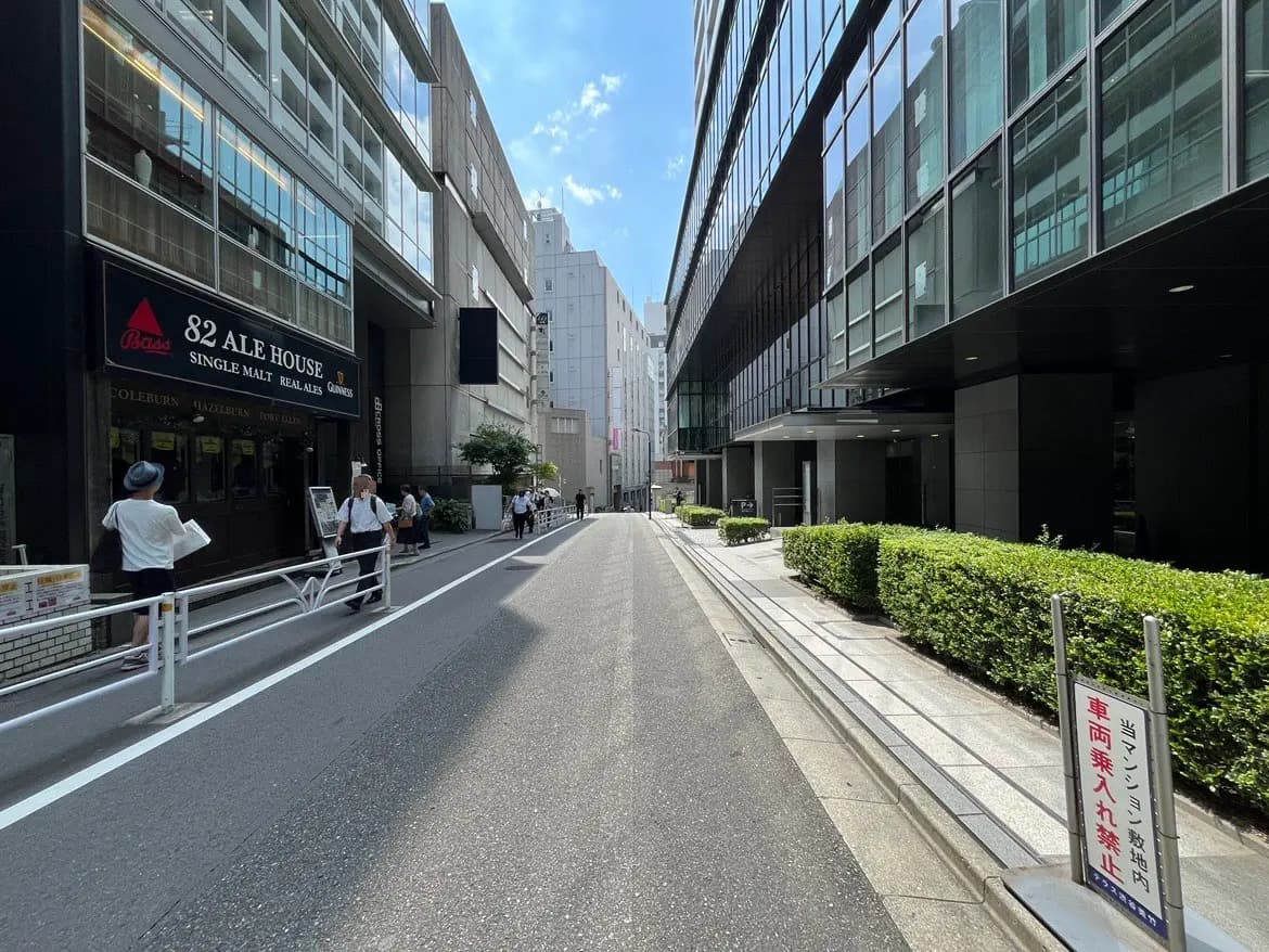 - 繁華街にある「82 ALE HOUSE」の外観、周囲を歩く人々と近代的なビル群が並ぶ街並みの風景