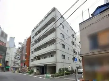 - 都市のビル群の中に佇む4階建てのマンション、シンプルな外観と周囲の街並みが映える景観