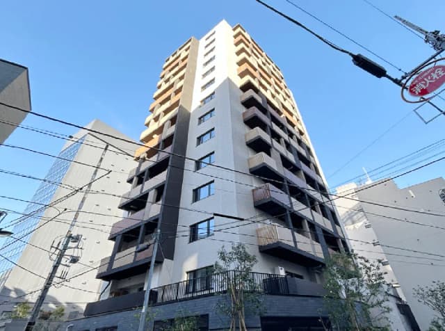 - 現代的なデザインの高層ビル、屋上テラスとバルコニーが特徴的で、青空を背景にした外観