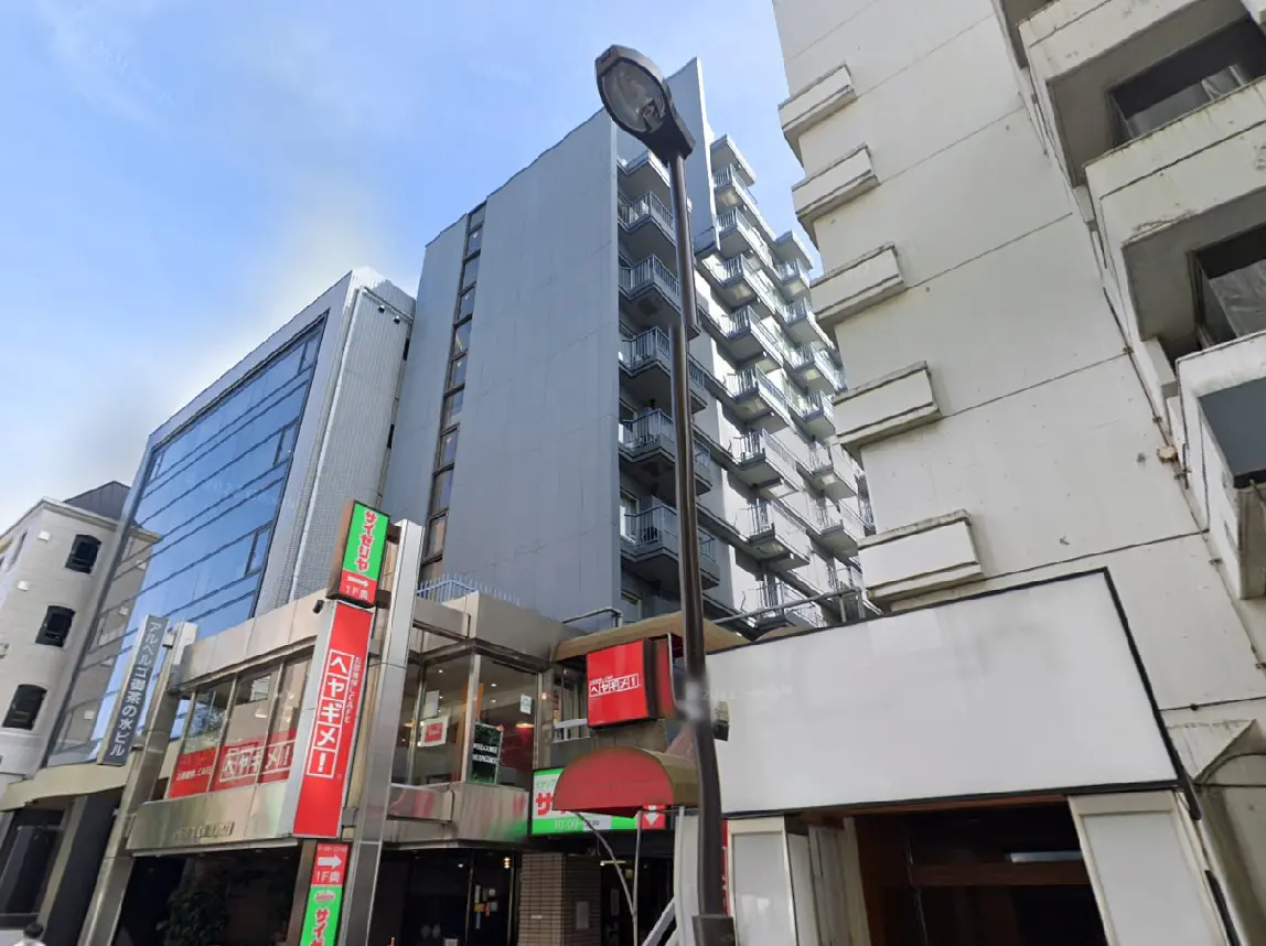 - 都市の風景に立つ現代的なビルと飲食店のファサード、周囲の高層ビルとのコントラストが際立つ街並み