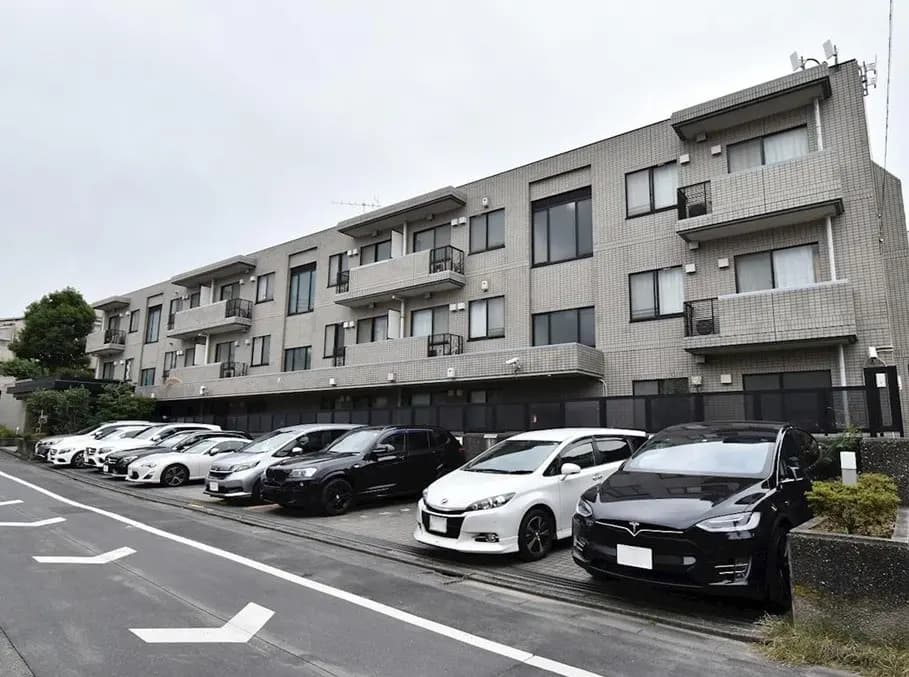 現代的なデザインの都市型アパート、駐車場に並ぶ車、クリアな空と建築外観