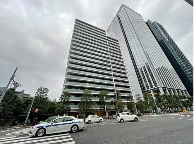 都市の交差点にあるモダンな高層ビル群、曇り空の下を走る車と歩行者の信号