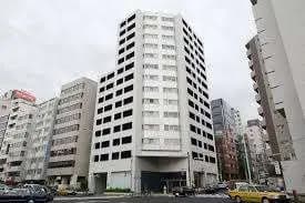 都市の風景と現代のマンションビル、グレーのファサード、周囲に建物と路上の車