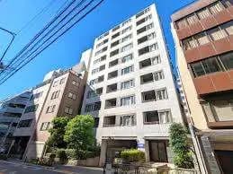 都市の中にある近代的なマンションの外観、晴れた日の青空と周囲の建物