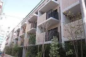現代的な外観のマンション、ベランダに緑の植物、都会の住宅街に位置する建物