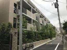 現代的なデザインのマンション、緑豊かな街路樹、クリーンな外観と都市生活