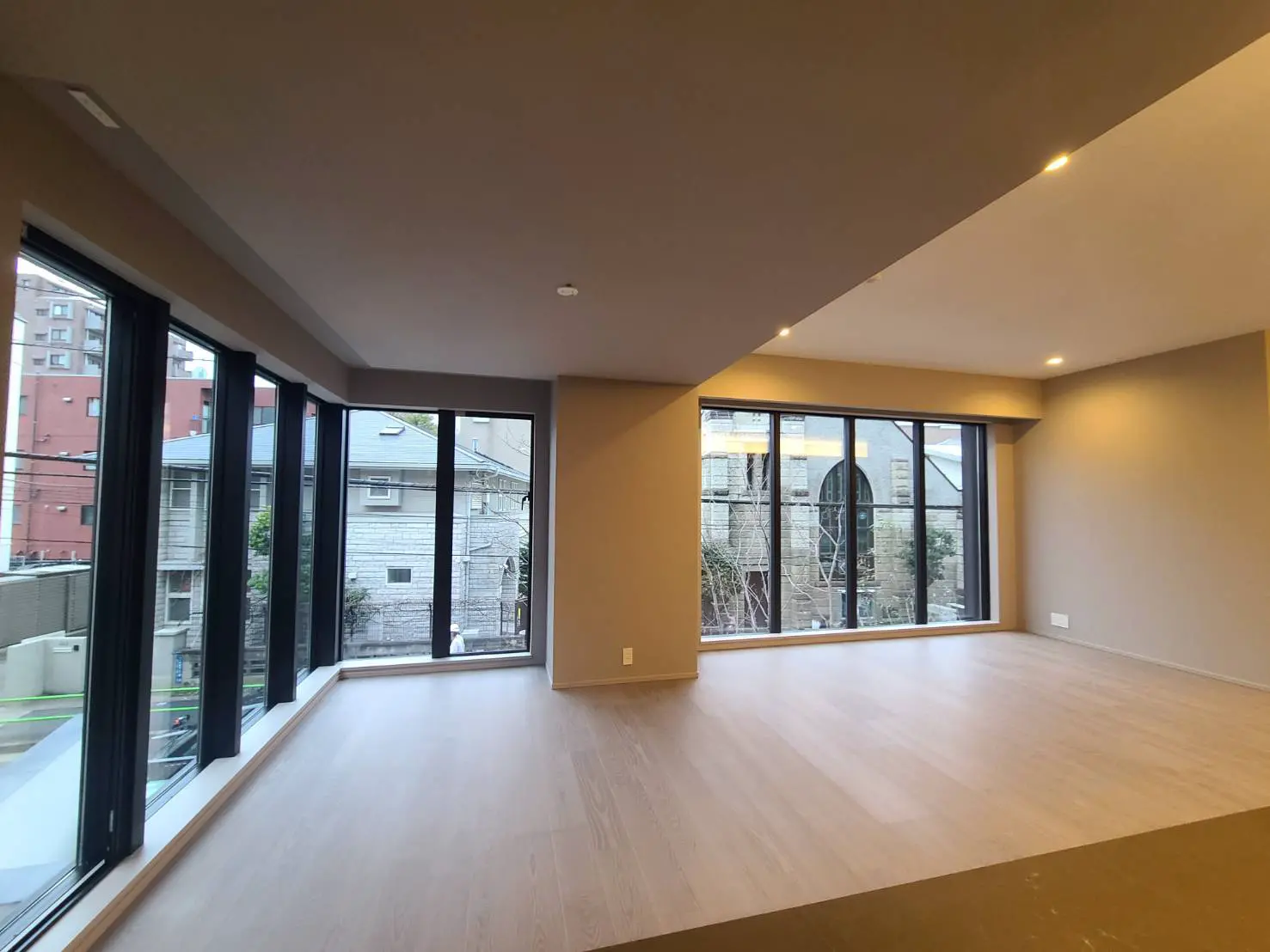 明るい室内と広々とした空間、フロアから天井までの大きな窓、モダンな都市型住宅のリビングルーム