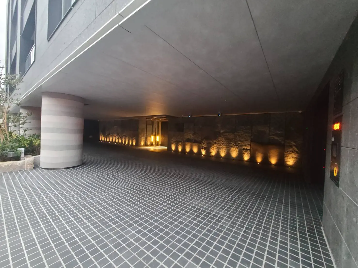 現代的な建築スタイルのビルのエントランス、照明が設置された通路と幾何学模様の床