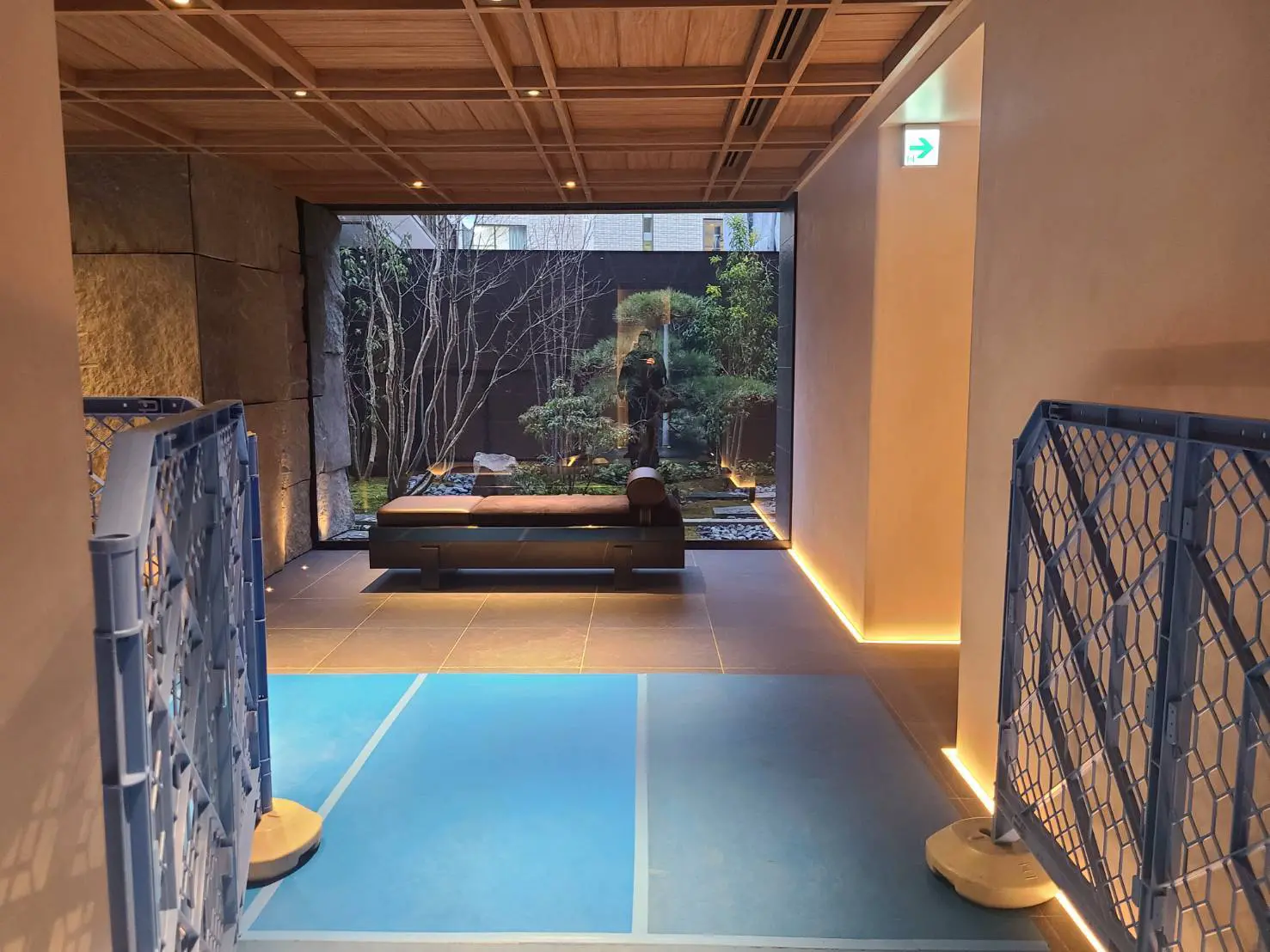 和風モダンな空間デザイン、間接照明があるリラックスエリア、青い床と木製の天井、庭園の眺め