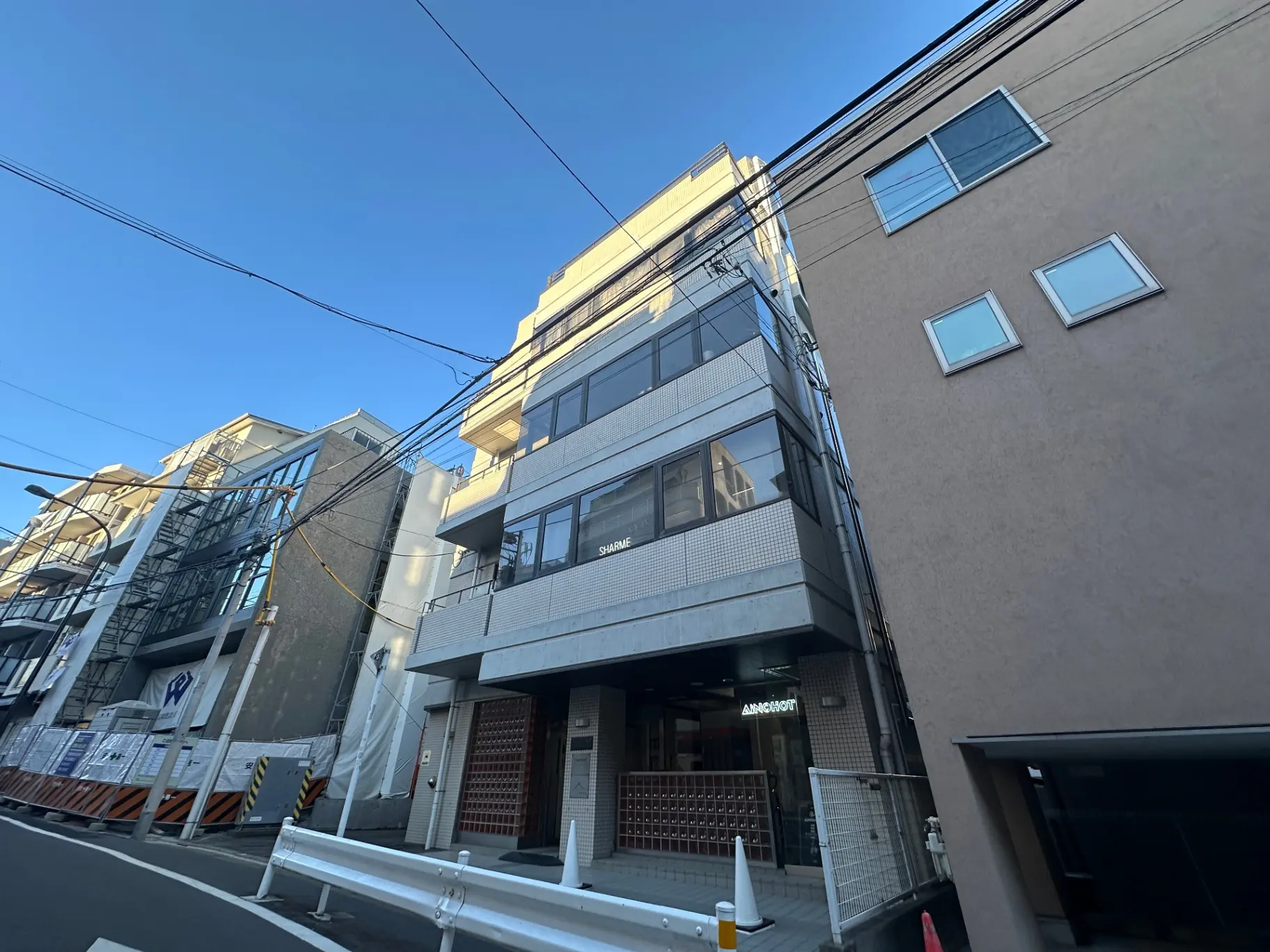 都市の建物と電線の風景、青空と夕暮れ時の光が映える外観