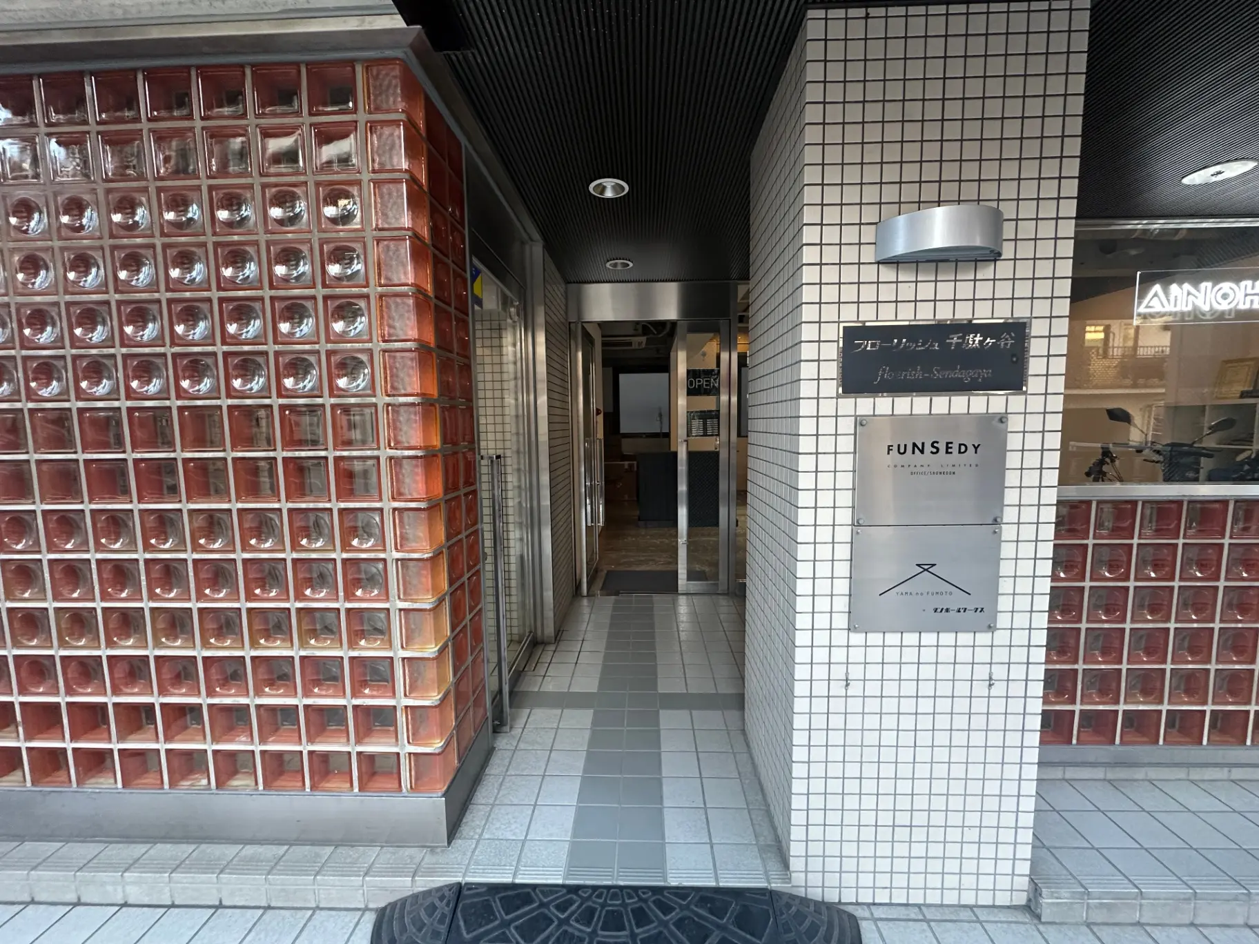 赤いガラスブロックと白いタイル壁の外観、ファッションストアFUNSEDYのエントランス