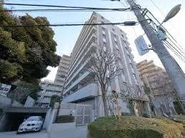 都市の坂道に立つ現代的なマンション、駐車スペースあり、日本のアパートメントの外観