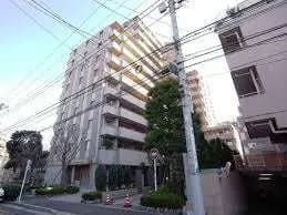 市街地に建つマンションの外観、電柱と道路標識が見える風景