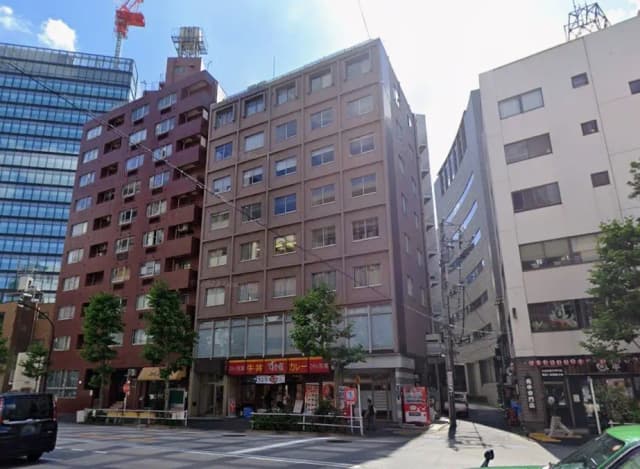 日本の都市部にあるビル群、クリアな青空、歩道と道路を写した景色