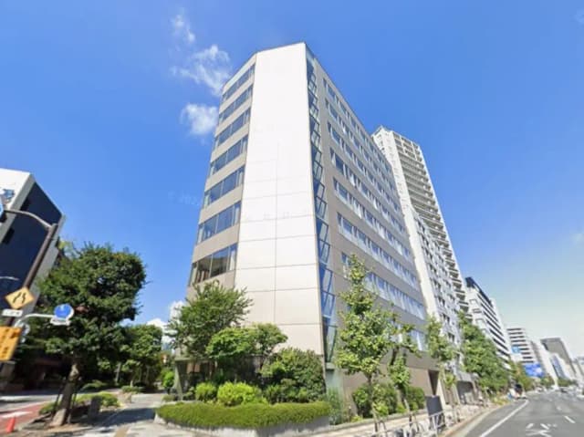 日本の都市部にあるモダンなオフィスビルとマンション、青空と緑の樹木が映える風景
