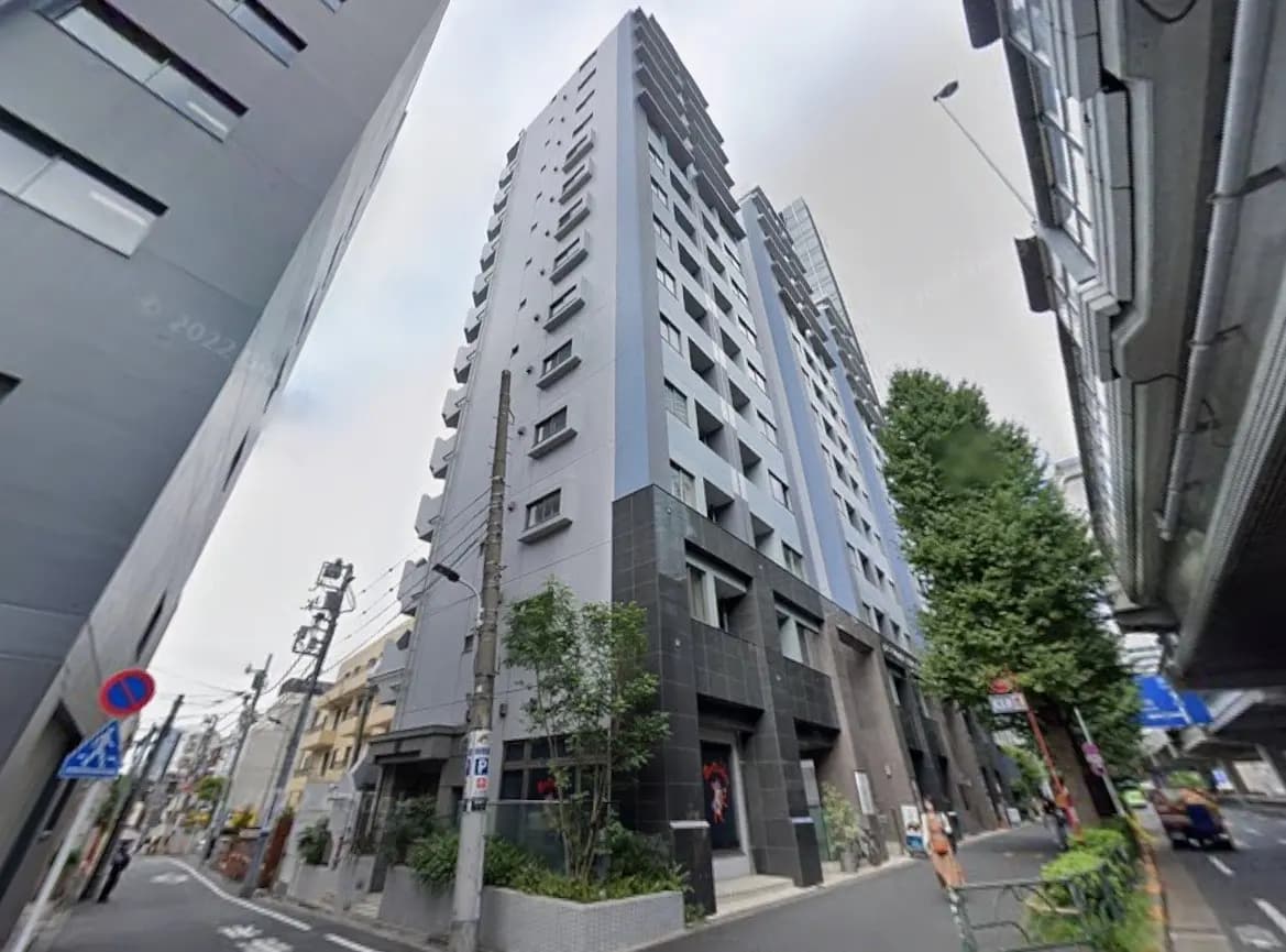 現代的なデザインの都市型マンション、グレーとブラックの外観、街路樹に囲まれた歩道