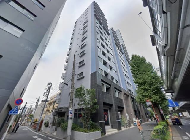 現代的なデザインの都市型マンション、グレーとブラックの外観、街路樹に囲まれた歩道