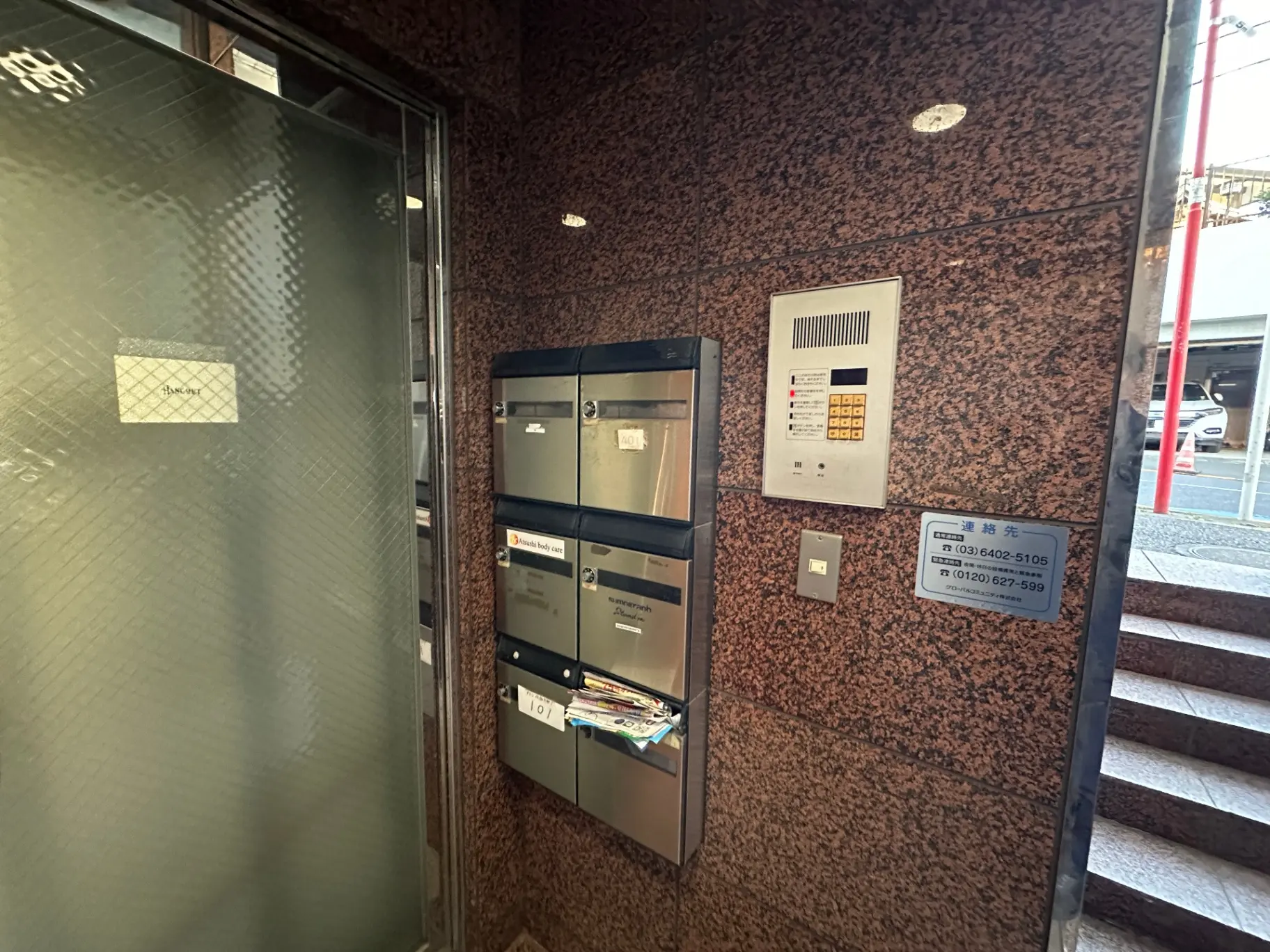 都会のマンションエントランス、セキュリティインターホンと郵便受けが設置された壁