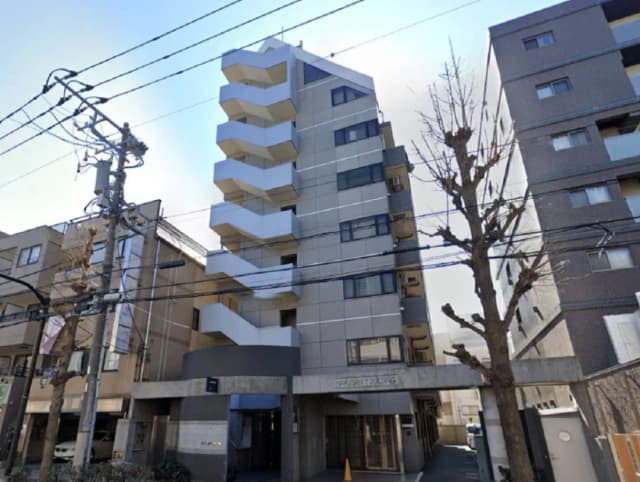 - シンプルでモダンな外観のマンション、バルコニー付きの階段状のデザインと周囲の建物が映る風景