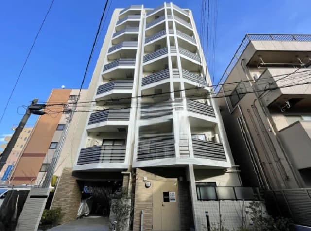 - 近代的な外観のマンション、バルコニー付きの階層構造、青空を背景にした建物の正面