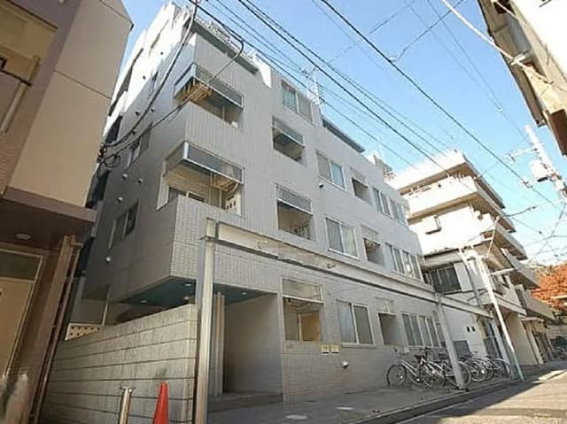 - モダンなデザインの集合住宅、明るい外観とバルコニー付きの窓、近隣に自転車が並ぶ通りの風景