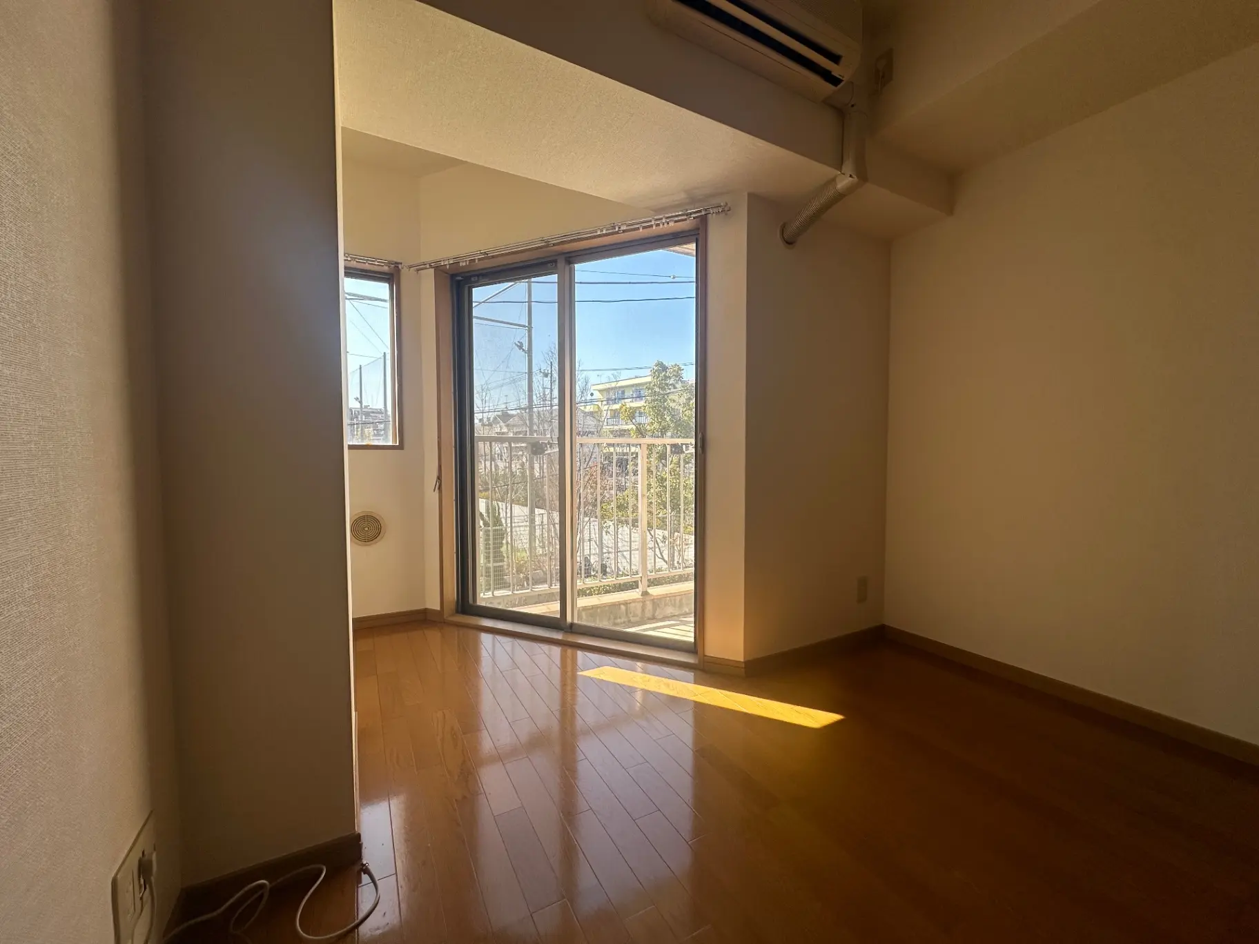 空の部屋の画像、日当たりの良い明るいリビングルーム、床は木材、バルコニー付き