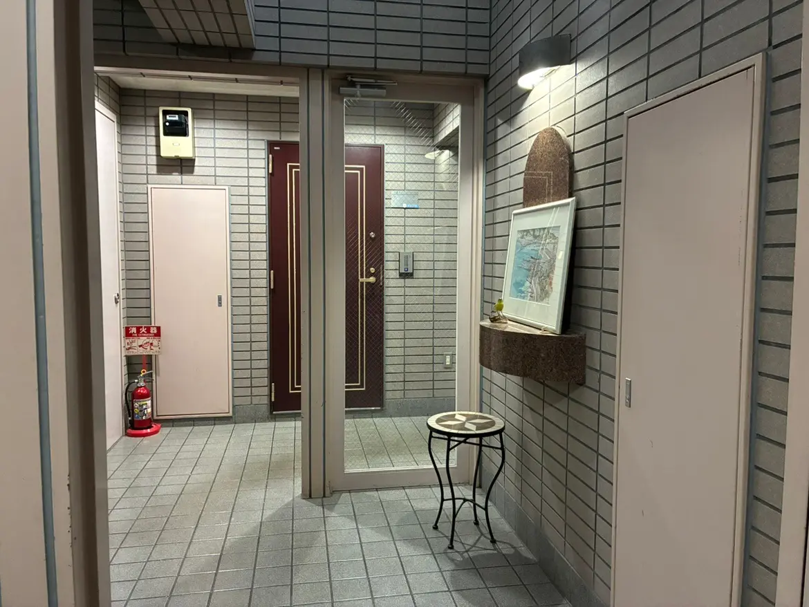 - モダンなデザインのエントランスホール、レンガ調の壁、アートが飾られた壁面、金属製のテーブルと火災警報器がある安全対策のインテリア